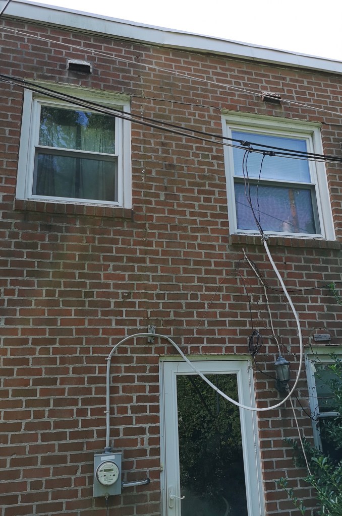 Wires hanging in front of a window and door, instead of neatly attached to the outside wall of the house.