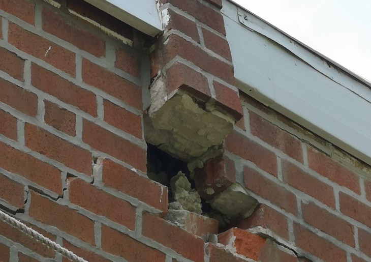 Missing bricks that were ripped out when the pole fell, due to the electrical wiring being connected to said bricks.